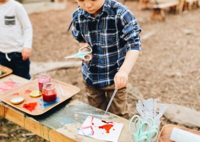 child holds scissors and works on art