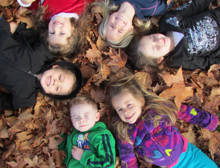 happy children lay in circle on leaves