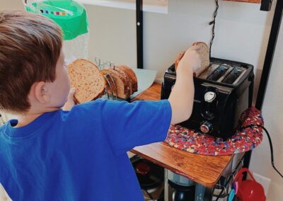 elementary student puts bread in toaster