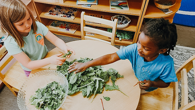 Two children prep green leafy vegetables