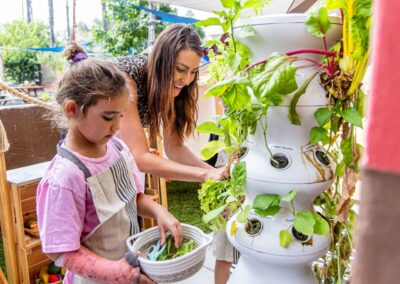 a teacher and a child harvesting leafy greens from a hyrdroponic tower