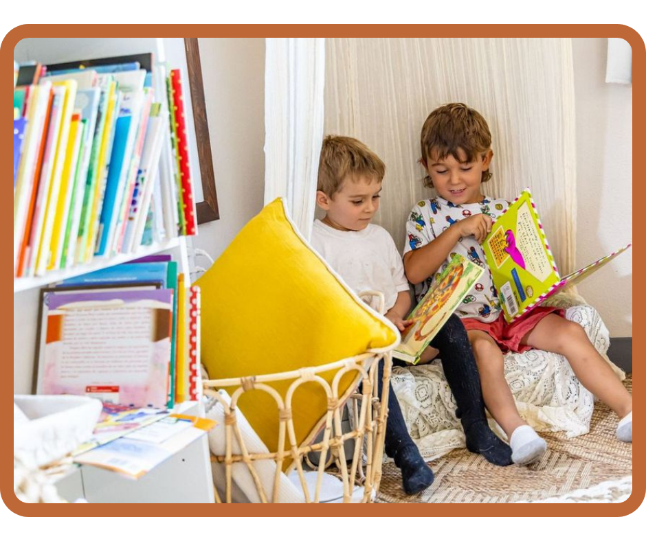 Two preschool children reading books together in a cozy tent-style reading nook with pillows